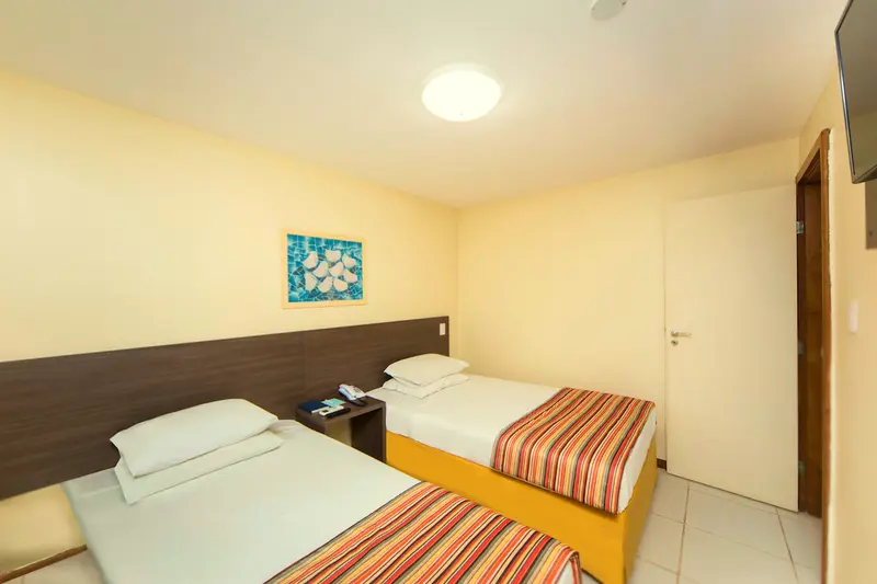 Segundo quarto do bangalô com duas camas de solteiro e cabeceira escura
