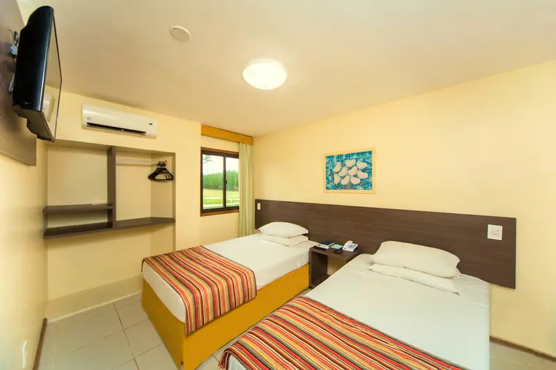 Quarto do bangalô com duas camas de solteiro, TV e ar-condicionado