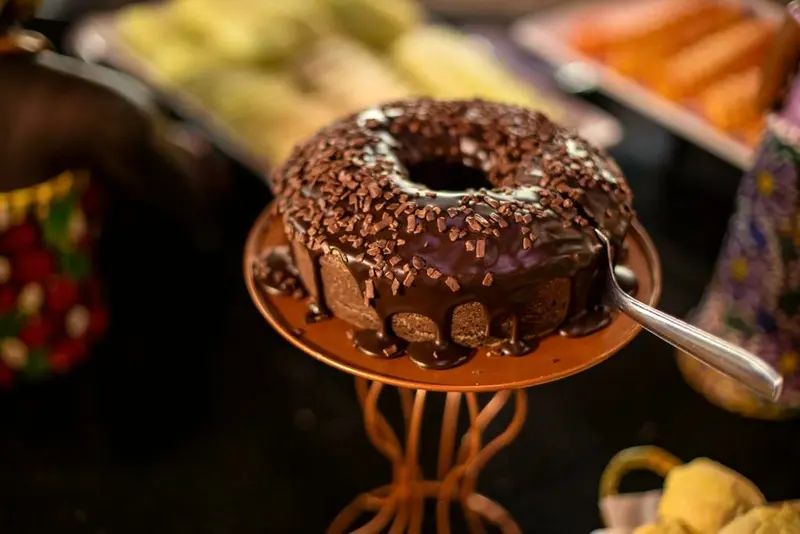 Bolo de chocolate com cobertura e granulado em suporte decorativo no bufê