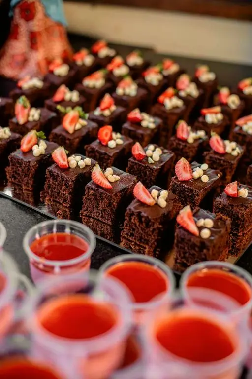 Quadradinhos de bolo de chocolate com morango e copinhos de gelatina vermelha