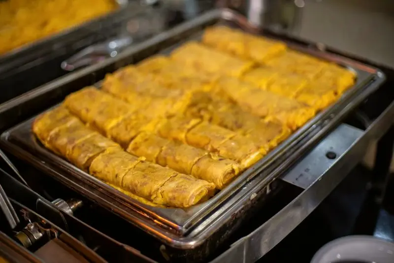 Bandeja de torta dourada cortada em quadrados na cuba aquecida do bufê