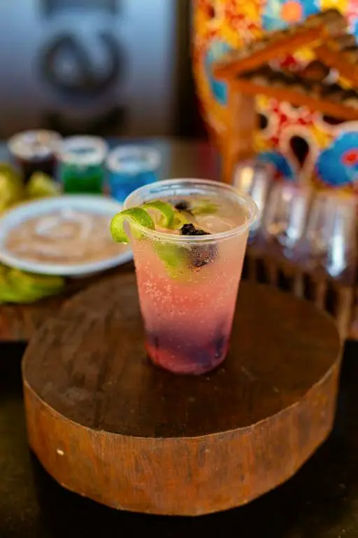 Drink rosado com gelo e limão sobre um tronco de madeira no bar