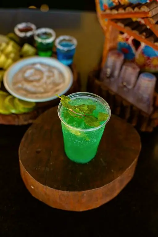 Drink verde com folhas de hortelã sobre um tronco de madeira no bar