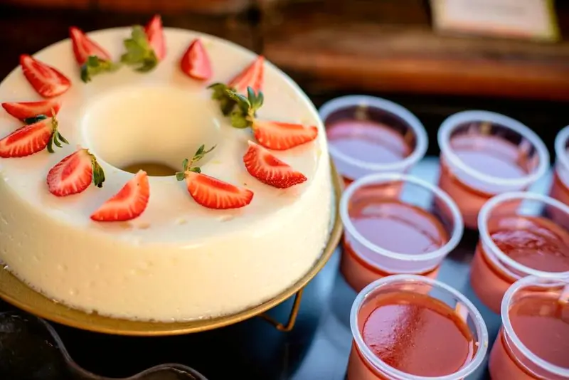 Pudim branco em anel decorado com morangos e copinhos de gelatina de morango