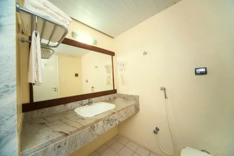 Banheiro do apartamento Superior com bancada de granito, espelho e chuveirinho