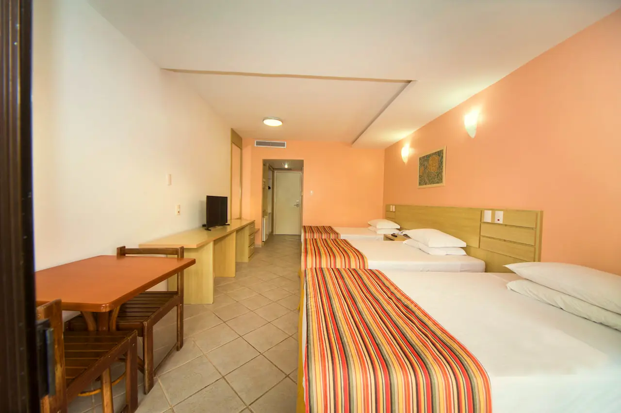 Apartamento Superior com camas, mesa de madeira, escrivaninha e TV