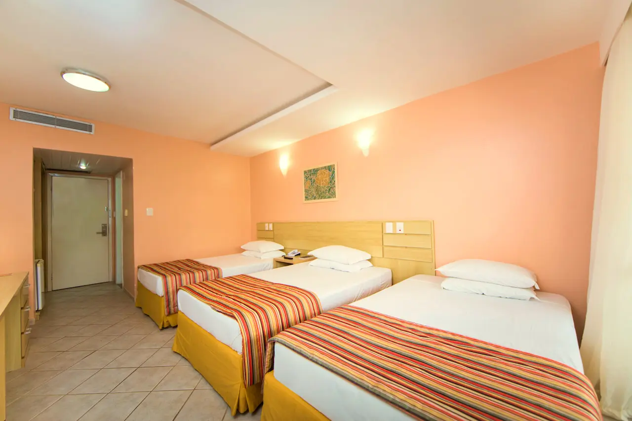 Apartamento Superior com três camas, paredes cor de pêssego e ar-condicionado