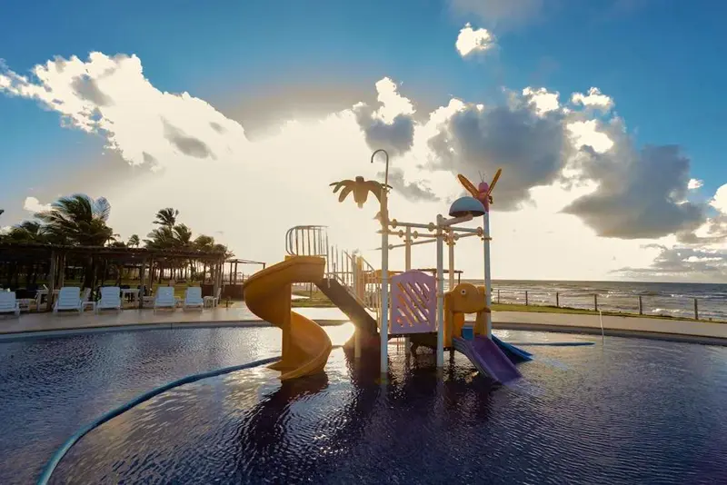 Playground aquático com toboáguas coloridos na piscina infantil, de frente para o mar
