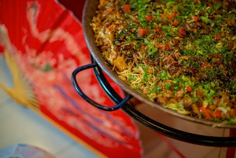 Wok com comida refogada sobre um leque vermelho decorativo
